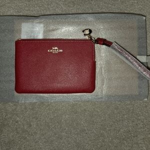 New Coach red corner zip wristlet in signature canvas comes with a Coach charm.
